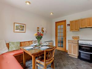 a living room with a table and a couch and a kitchen at 3 Bed in The Cairngorms IN515 in Laggan