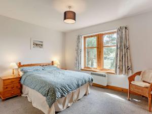 a bedroom with a bed and a window and a chair at 3 Bed in The Cairngorms IN515 in Laggan
