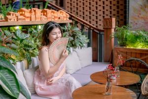 a girl sitting on a couch holding a fan at Seahorse Han Market Da Nang Hostel by Haviland in Da Nang