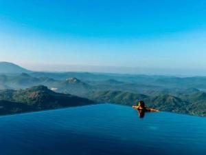 a woman swimming in the water in the mountains at GreenAcres Leisure Resort in Kandy