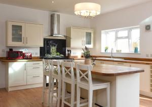 a kitchen with white cabinets and a island with bar stools at 5 Bed Chic Modern House, Spacious - Sleeps 11, Off-Road Parking - Great for groups & Contractors - By Blue Puffin Stays in Waterlooville