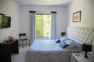 een slaapkamer met een bed met blauwe kussens en een raam bij HOTEL POUSADA PARAÍSO in Itapevy