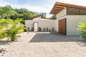 biały dom z drewnianymi drzwiami i palmami w obiekcie Casa Tranquila BRAND NEW Villa with Pool w mieście Sámara