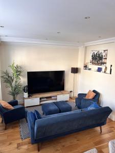 sala de estar con sofás azules y TV de pantalla plana en Bond MAYFAIR, en Londres