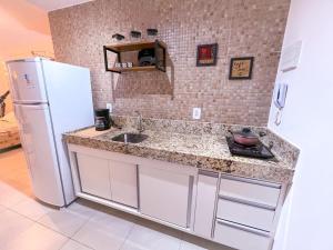 a kitchen with a sink and a white refrigerator at Ap standard confort bem localizado in Campina Grande