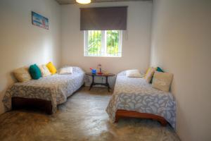a room with two beds and a table in it at La Case Creole in Roches Noires
