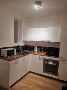 a kitchen with white cabinets and a sink and a microwave at *Appartement Moderne/2 minutes du métro* in Saint-Ouen