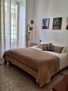 ALLOGGIO CENTRALISSIMO SANREMO في سانريمو: غرفة نوم بسرير كبير مع صورتين على الحائط