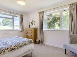 a bedroom with a bed and a chair and windows at 3 Bed in Ashford In The Water 88675 in Great Longstone