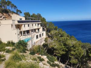 a building on a hill next to the ocean at Finca S' Estoneta con increíbles vistas al mar in Capdepera