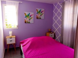een slaapkamer met een roze bed en een paarse muur bij Studio avec jardin et wifi a Le Moule a 5 km de la plage in Le Moule