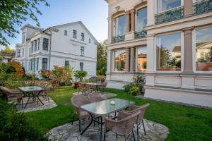 a patio with tables and chairs in the yard of a house at Villa Stock Appartement mit großer Veranda in Heringsdorf