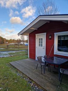 Lovsjöbadens Camping في يونيشوبينغ: سطح خشبي مع طاولة وكراسي على المنزل