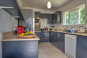 una cocina con armarios azules y un bol de fruta en la barra en La Case Creole, en Roches Noires