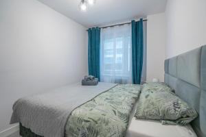 een slaapkamer met een bed en een raam met blauwe gordijnen bij Stylowy apartament Blue ~self check in 24h in Wrocław