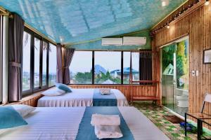 two beds in a room with large windows at Hang Mua Bamboo Homestay Ninh Binh in Ninh Binh