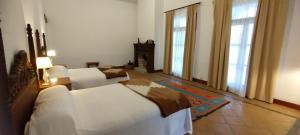 a bedroom with two white beds and two windows at Finca El Recreo in Cafayate
