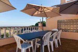 una mesa y sillas en un balcón con sombrilla en Villa Sol, en Sant Cebrià de Vallalta
