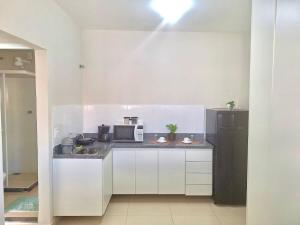 uma cozinha com armários brancos e um frigorífico preto em Studio #1 Conforto em Campos dos Goytacazes