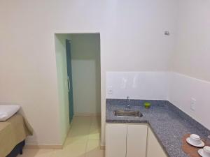 uma cozinha com um lavatório e um quarto com uma cama em Studio #1 Conforto em Campos dos Goytacazes