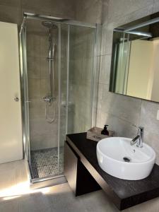 La salle de bains est pourvue d'un lavabo blanc et d'une douche. dans l'établissement CASA DOS CEDROS, à Pico da Pedra