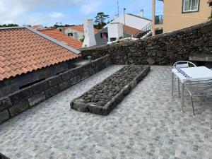 eine Terrasse mit einem Tisch und einer Steinmauer in der Unterkunft CASA DOS CEDROS in Pico da Pedra