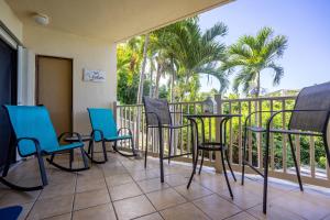 einen Balkon mit Stühlen, Tischen und Palmen in der Unterkunft Blue Moon Villa at Point Pleasant Resort condo in Frydendal