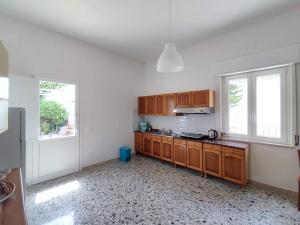 an empty kitchen with wooden cabinets and windows at l'Araucaria casa vacanze in Marsala