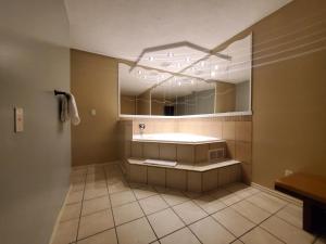 Super 8 by Wyndham Duncan في دانكن: حمام مع حوض ومرآة كبيرة