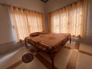 Khātuにあるगणेश फेमिली गेस्ट हाउसのカーテン付きのベッドルーム1室(ベッド1台付)