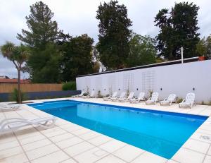 a swimming pool with lounge chairs next to a building at Balcón Edén Apart in La Falda