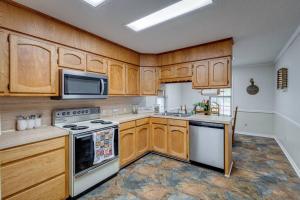 La cuisine est équipée de placards en bois et d'un four avec plaques de cuisson. dans l'établissement Rustic Flames & 4-Bedroom Comfort, à West Monroe