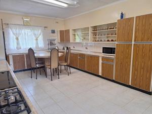 a kitchen with wooden cabinets and a table and chairs at Charming 6-Bed House with Swimming Pool in Harare in Harare