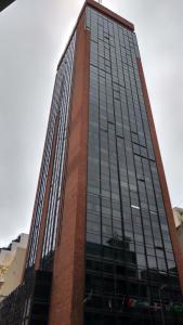 wysoki budynek z czerwonej cegły i szklanymi oknami w obiekcie Apartments Tower w BuenosAires