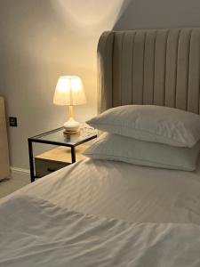 Una cama con una mesa con una lámpara. en الفاتن لشقق الخاصه en Riad