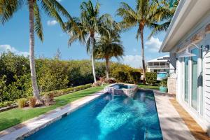 a swimming pool next to a house with palm trees at Luxurious Haven in Tavernier