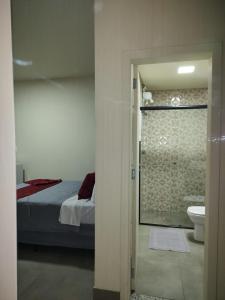 a bedroom with a bed and a bathroom with a shower at Morada Stucchi in Balneário Camboriú