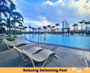 uma piscina com duas cadeiras brancas e palmeiras em Trion @ Kuala Lumpur near KLCC TRX by Cityscape em Kuala Lumpur