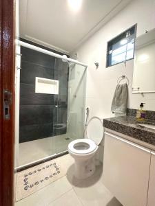 uma casa de banho com um WC e uma cabina de duche em vidro. em Apartamentos na Ponta dos Castelhanos - Anchieta em Anchieta