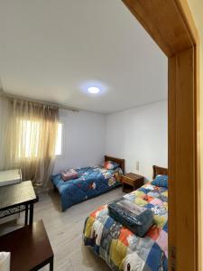 1 Schlafzimmer mit 2 Betten, einem Tisch und einem Schreibtisch in der Unterkunft Lovely family apartment in Tetouan in Tétouan