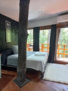 1 dormitorio con 1 cama junto a un árbol en Jack y Rouse suites de mar en Mar de las Pampas