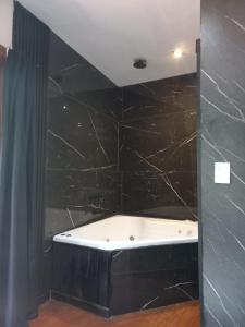 een badkamer met een bad en zwarte tegels bij Jack y Rouse suites de mar in Mar de las Pampas
