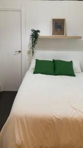Una cama blanca con una almohada verde. en Corrala en el Madrid histórico, en Madrid