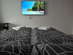 un televisor colgado en una pared sobre una cama en Summer Haven- self check-in, parking, netflix, terrace, near mall, en Oradea