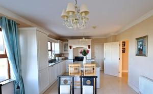 een keuken met een tafel en stoelen en een kroonluchter bij The Cliffs of Moher Holiday House in Doolin