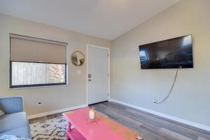 a living room with a table and a tv on the wall at Ideally Located Palm Harbor Condo Walk Downtown! in Palm Harbor