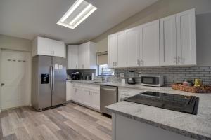 a kitchen with white cabinets and a stainless steel refrigerator at Ideally Located Palm Harbor Condo Walk Downtown! in Palm Harbor