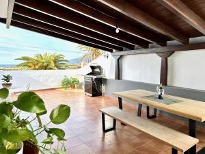 a patio with a wooden table and a grill at Alcalá Retreat: Ocean View & Modern Comfort in Alcalá