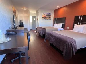 Cette chambre comprend deux lits et un bureau. dans l'établissement Budget Inn of Okeechobee, à Okeechobee