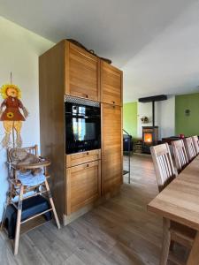 a kitchen with a wooden cabinet and a dining room at Le Bleu de B Bresse 4 étoiles in Saint-Étienne-en-Bresse